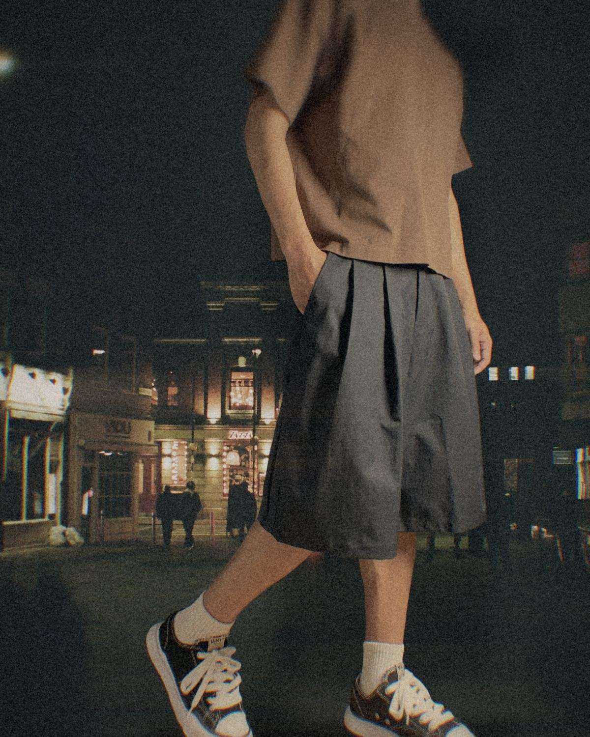 夜晚街上走路的人，穿黑色打褶寬版短褲